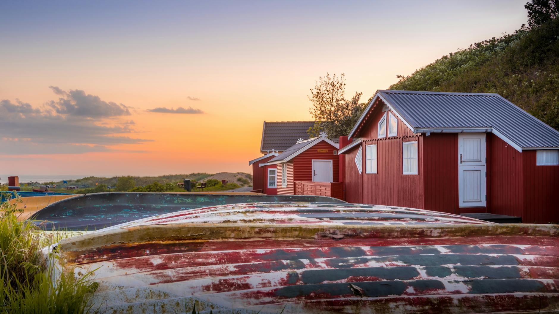 Czerwone drewniane domki nad spokojnym jeziorem o zachodzie słońca