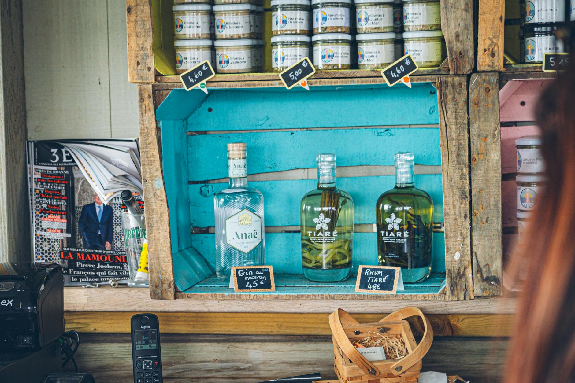 Drewniana półka z butelkami ginu i rumu z ręcznie wypisanymi cenami