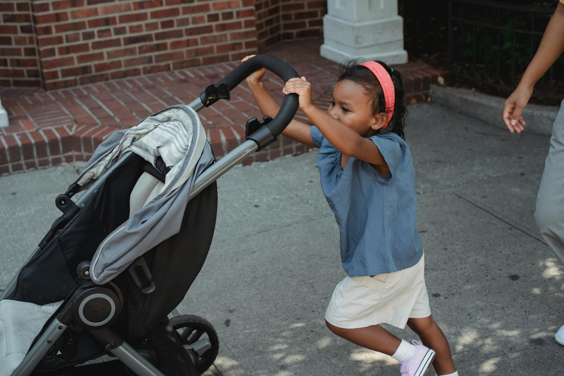 Dziecko pcha wózek spacerowy w słoneczny dzień w parku