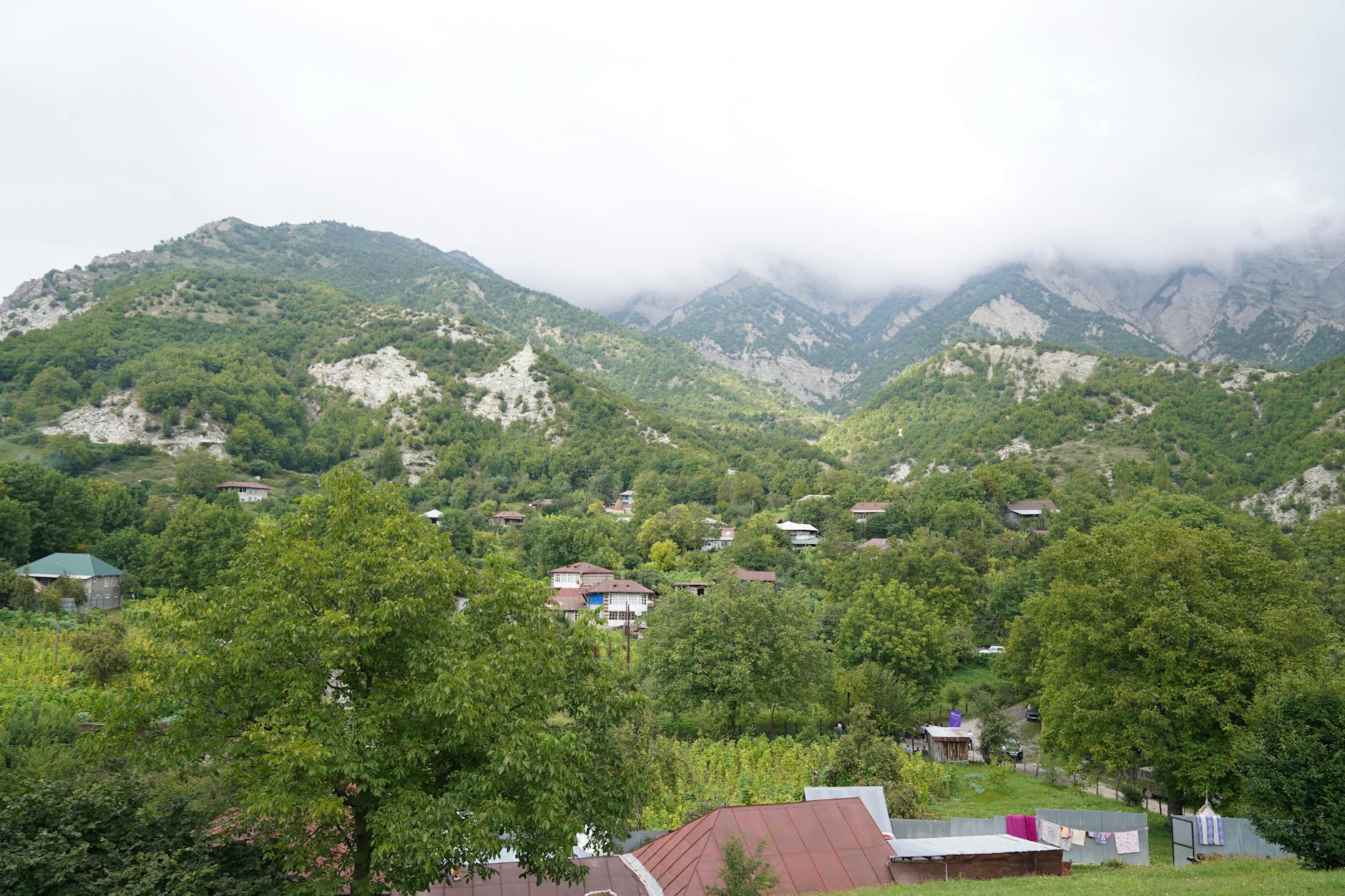 Górska wieś otoczona zielonymi wzgórzami pod zachmurzonym niebem