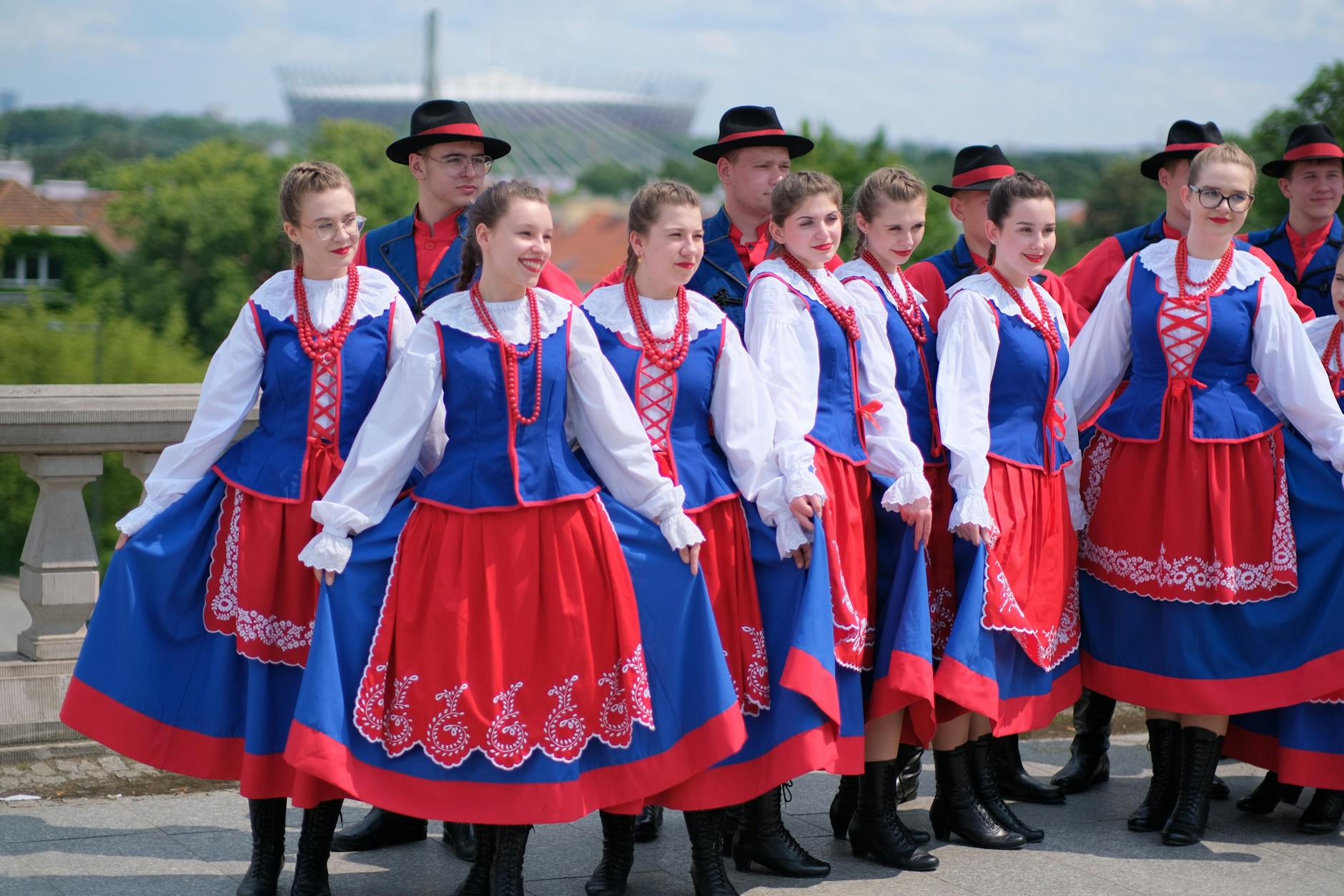 Grupa osób w tradycyjnych polskich strojach ludowych na dworze