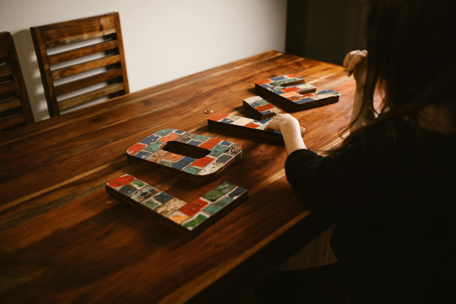 Kobieta układa kolorowe literowe mozaiki na drewnianym stole