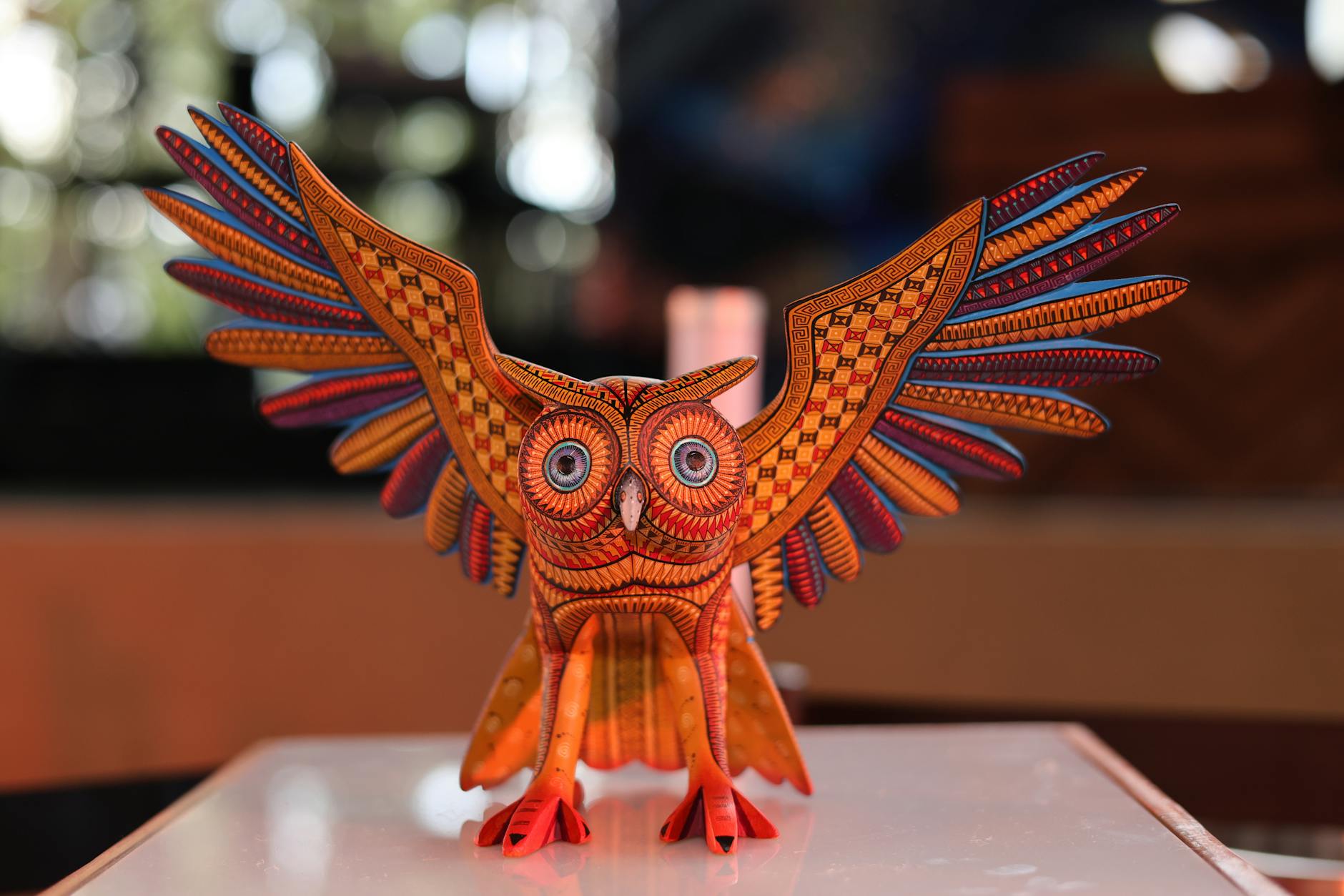 Kolorowa rzeźba sowy alebrije z misternymi wzorami w muzealnej gablocie