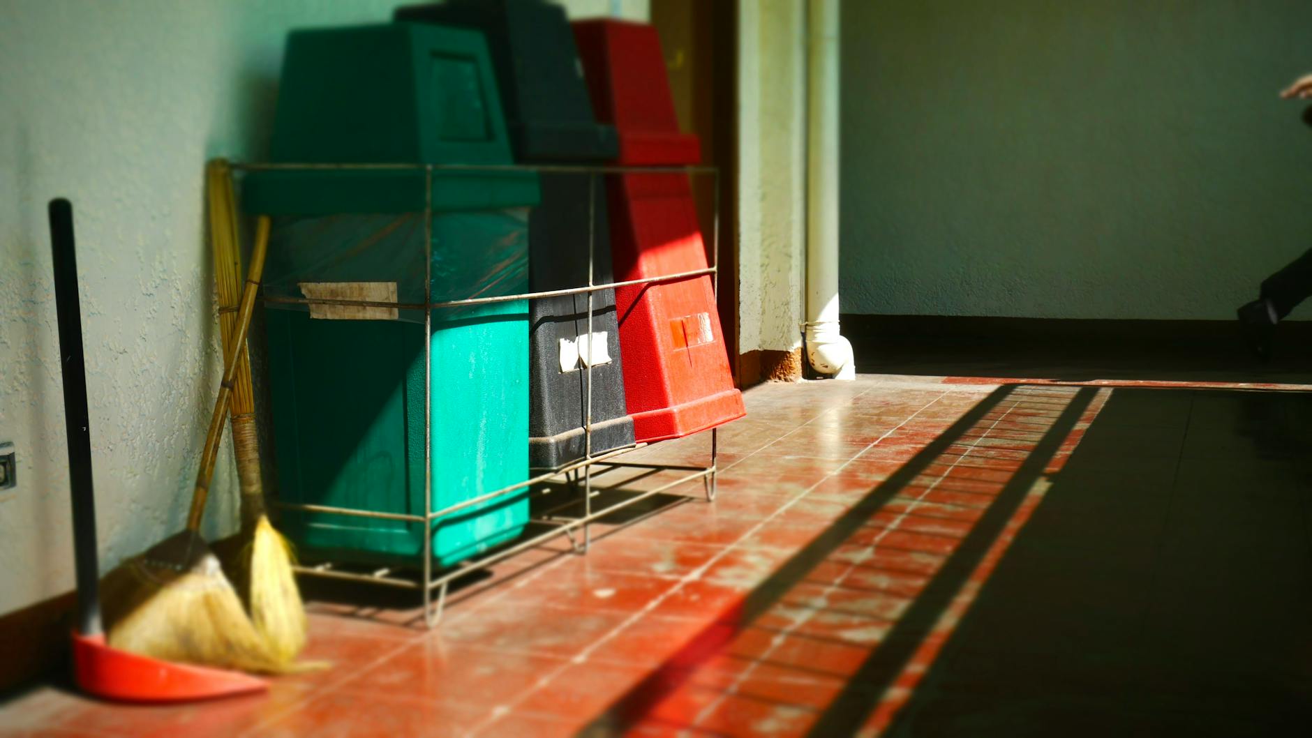 Wózek z pojemnikami na odpady i mopem w jasnym korytarzu