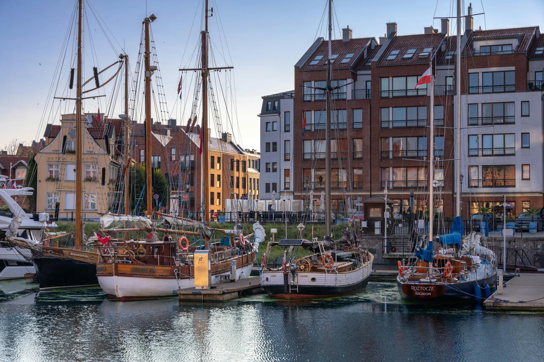 Zachód słońca nad mariną w Gdańsku z żaglówkami i zabytkowymi kamienicami