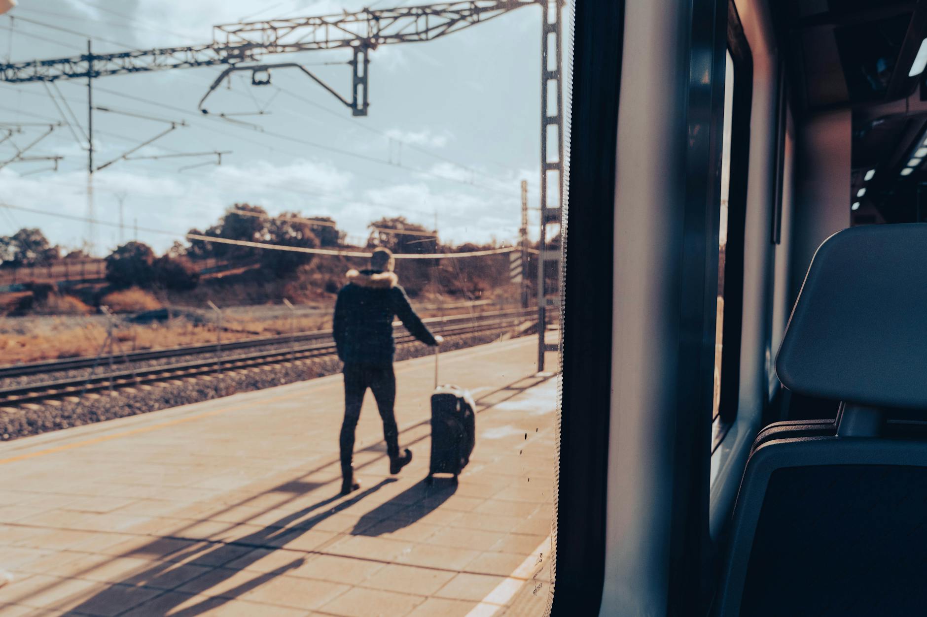 Mężczyzna z walizką na peronie oglądany z okna pociągu