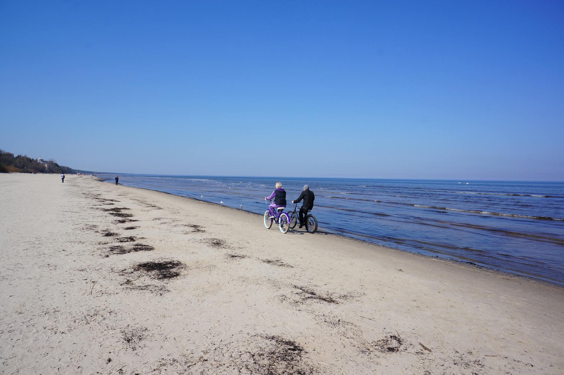 Para na rowerach jedzie wzdłuż piaszczystej plaży nad spokojnym morzem