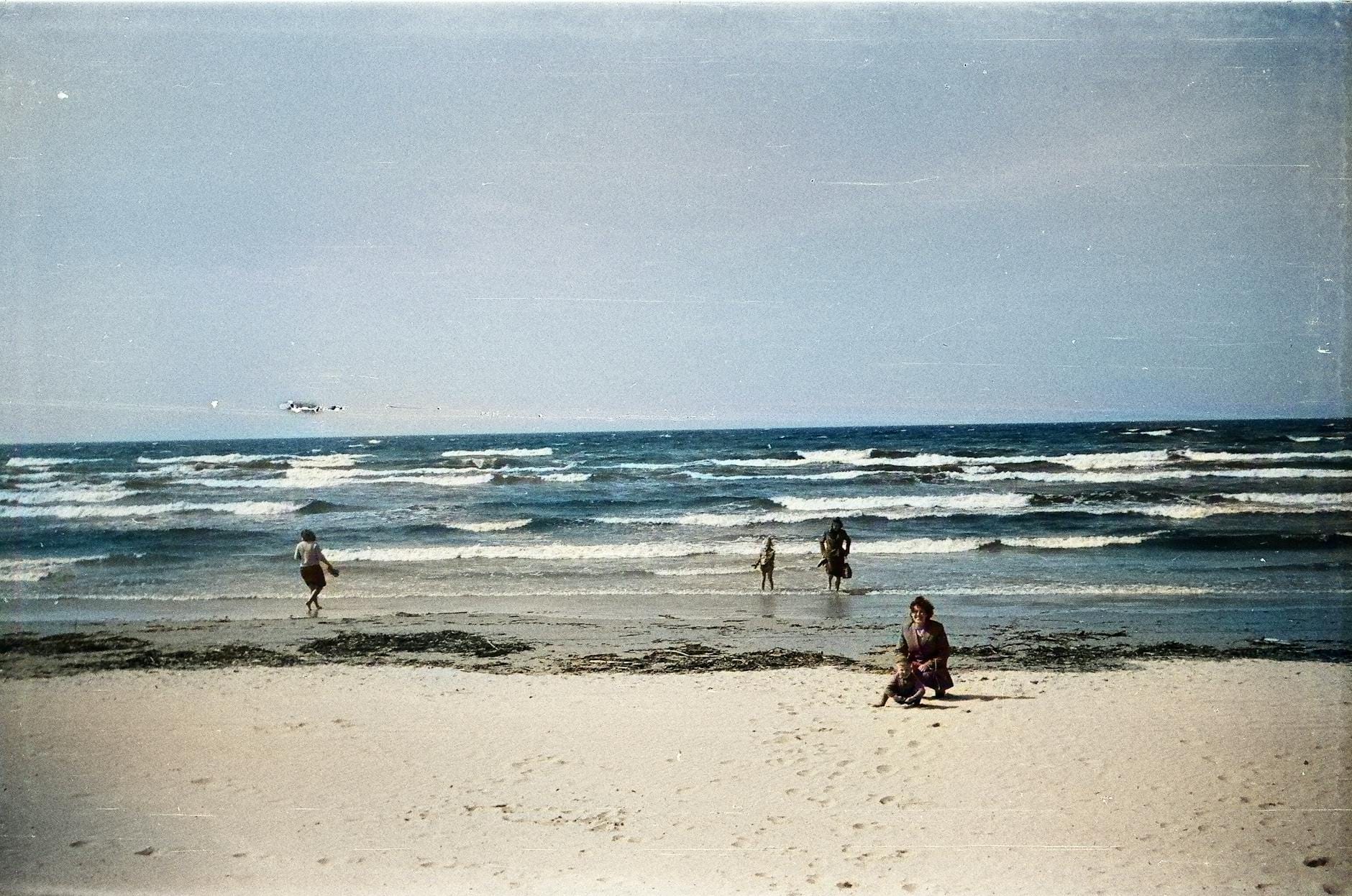 Rodzina spaceruje po spokojnej, piaszczystej plaży nad Bałtykiem