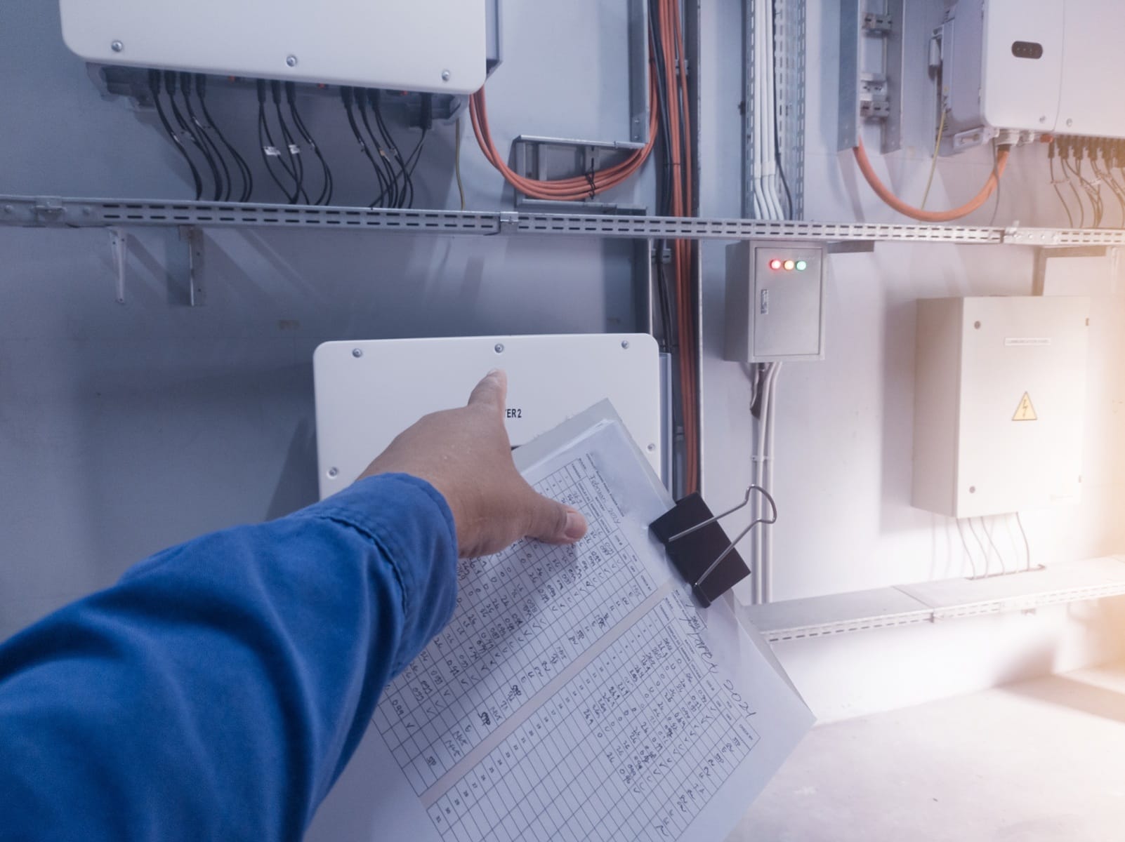 Falownik hybrydowy łączący panele słoneczne, magazyn energii i sieć energetyczną w firmie produkcyjnej.