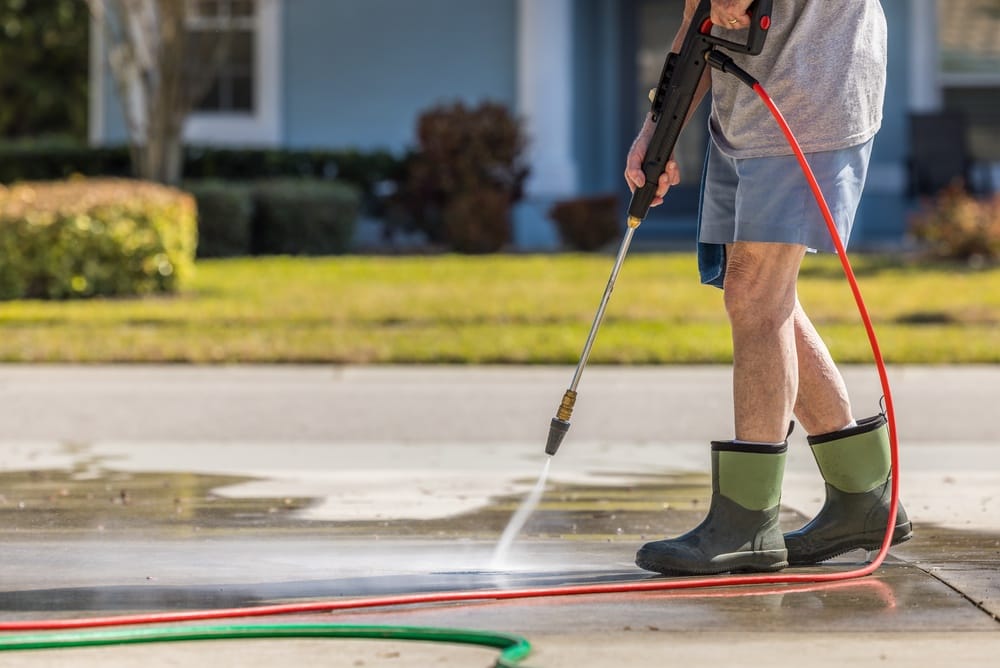 Man,Using,Pressure,Washer,To,Power,Wash,Residential,Concrete,Driveway